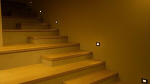 Un escalier avec des marches en bois et des lampes fixées au mur.