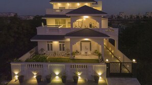 A multi-story house with a balcony, a staircase, and a well-lit entrance. - Anagha Homestay Home Away From Home (Udaipur)