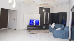 A modern living room with a flat-screen TV, a blue sofa, and a grey rug. - Palmas Hostel (Palmas)
