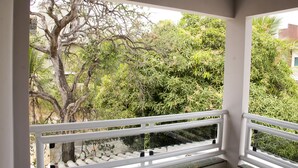 A balcony with a white railing, a view of a tree, and dense foliage. - Palmas Hostel (Palmas)