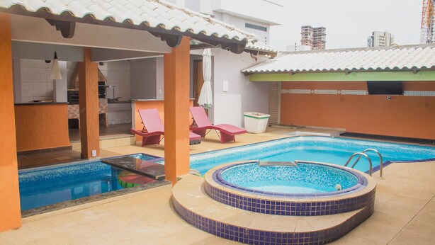 A swimming pool area with a hot tub, lounge chairs, and a covered seating area. - Palmas Hostel (Palmas)