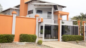 A modern two-story building with a balcony, a gated entrance, and a small garden area. - Palmas Hostel (Palmas)