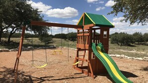 A playground with a wooden slide and swings. - Your next, beautiful getaway! (Hunt)