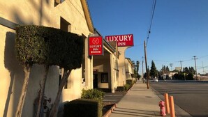 A building with a sign for 'Luxury Inn' and a fire hydrant on the sidewalk. - Luxury Inn (Norwalk)