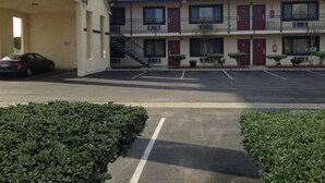 A motel with a two-story structure, a covered parking area, and a single-story building adjacent to it. - Luxury Inn (Norwalk)