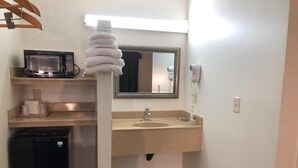 A bathroom with a sink, mirror, hairdryer, and a microwave on a shelf. - Luxury Inn (Norwalk)