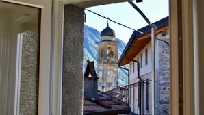 Vista a través de una ventana que muestra un edificio con fachada de piedra y una torre del reloj al fondo.