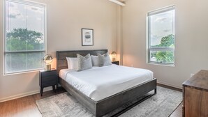 A bedroom with a bed, bedside tables, a ceiling fan, and two windows with blinds. - Mint House Greenville Downtown by Kasa (Greenville)