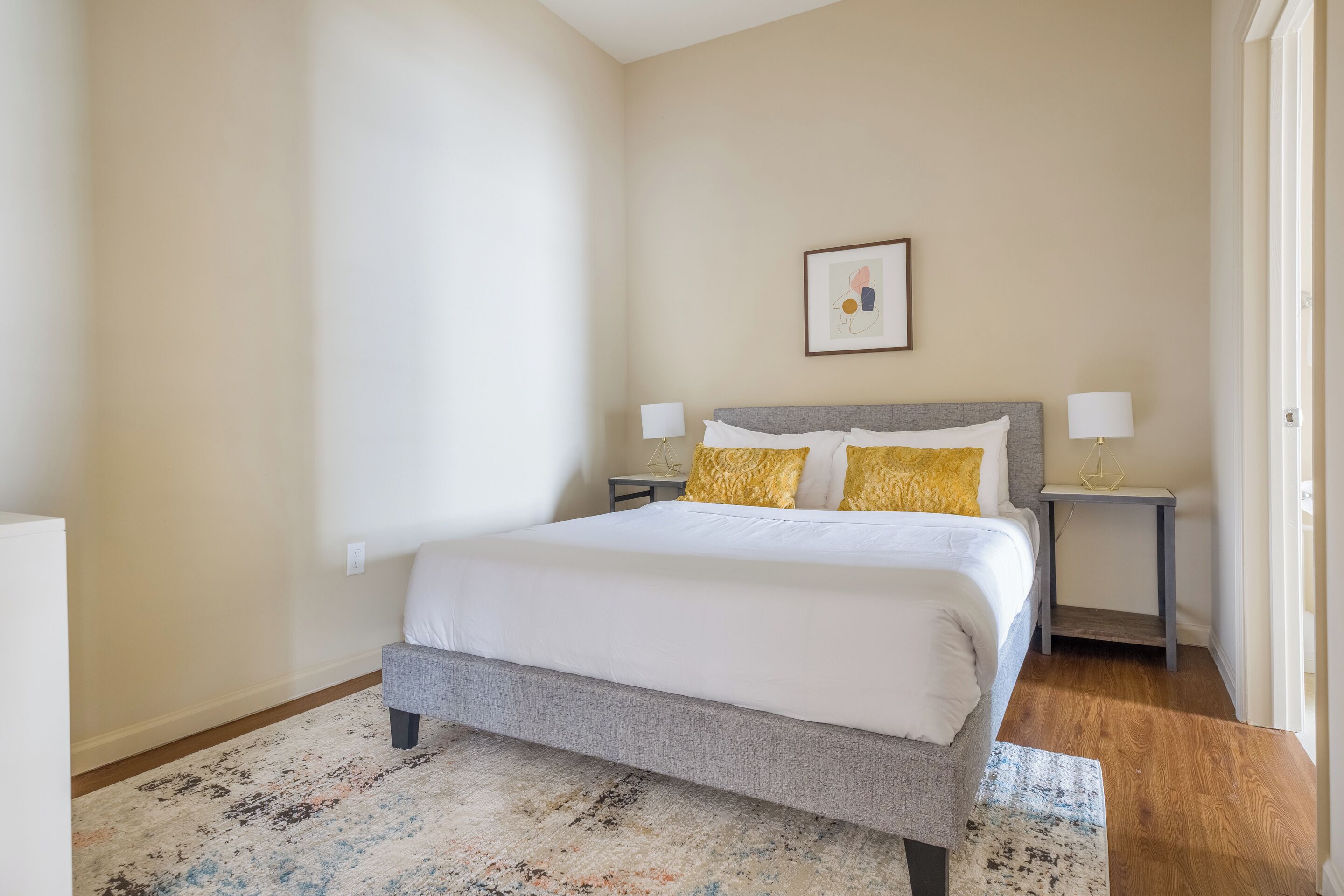Un dormitorio con una cama grande, dos mesitas de noche y un cuadro enmarcado en la pared.