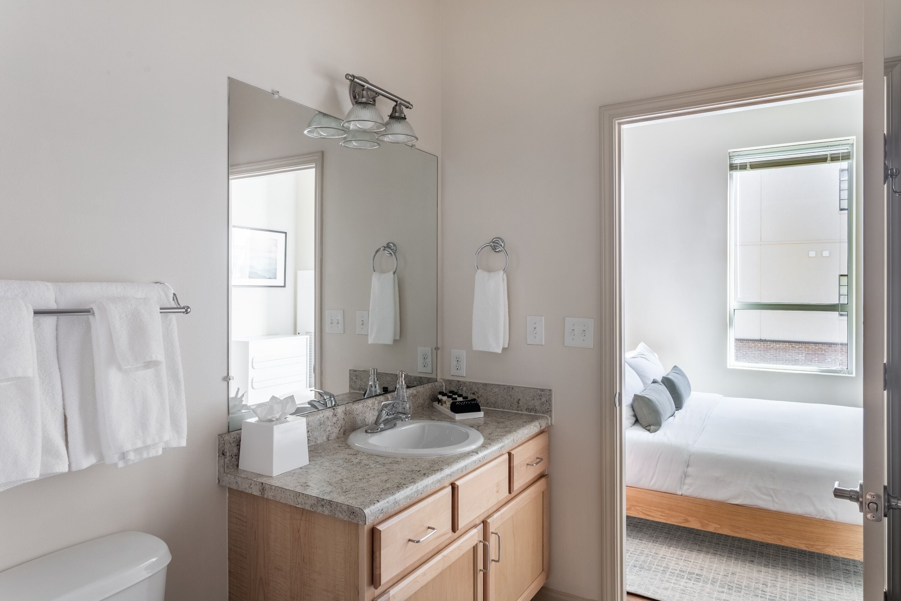 A modern bathroom with a sink, mirror, and towel rack.