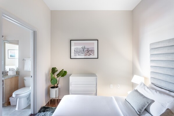 A modern bedroom with a bed, bedside table, and a framed picture on the wall.