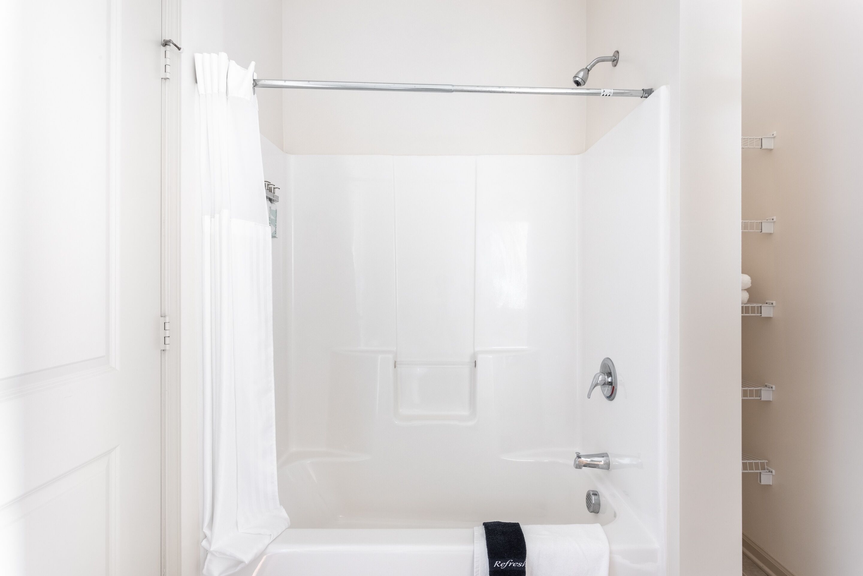 A modern bathroom with a glass shower enclosure, a towel rack, and a toilet paper holder.