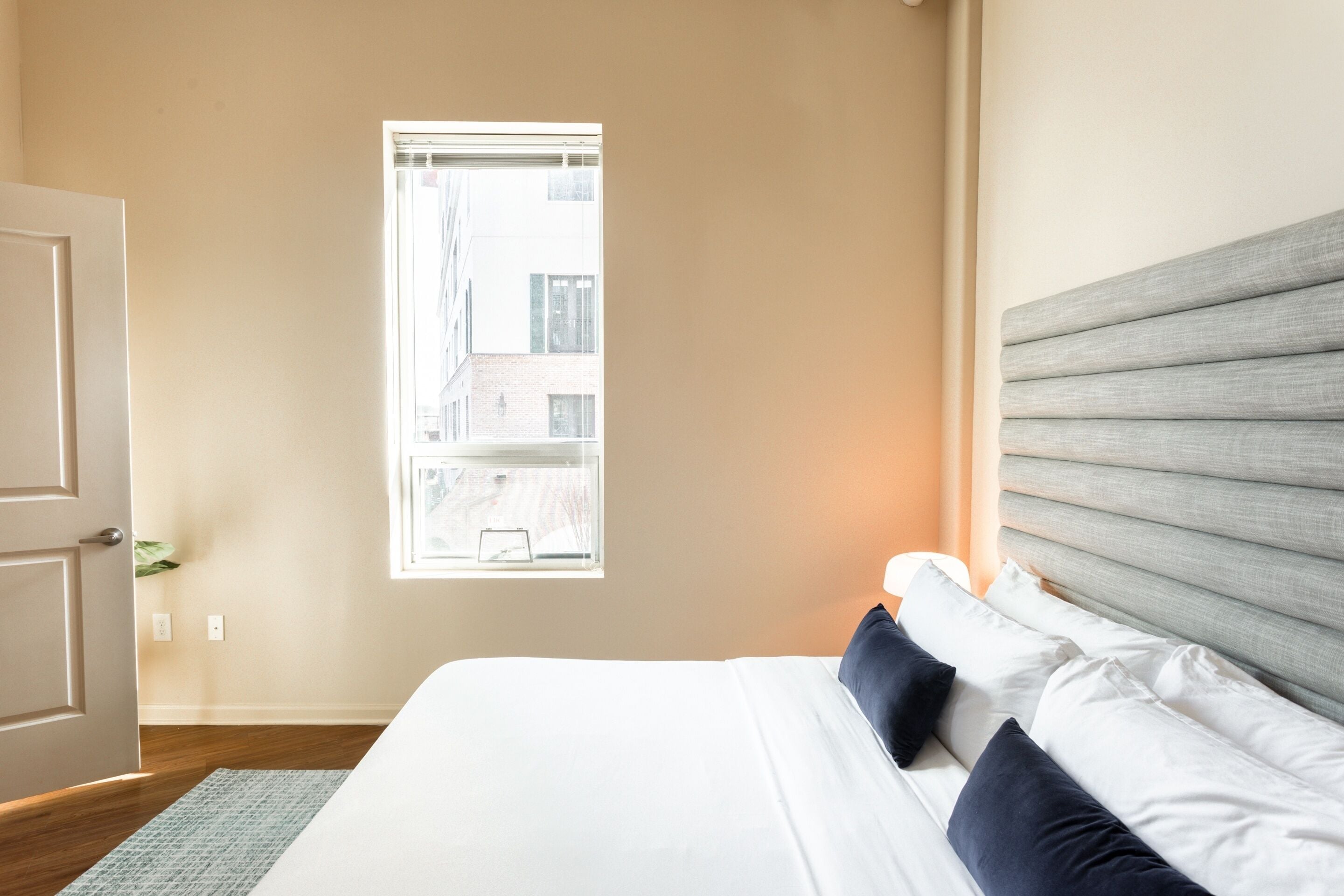 A bedroom with a bed, a window, and a door.
