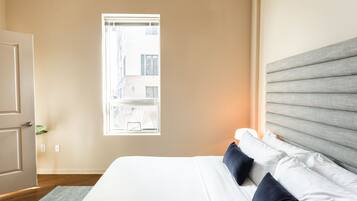 A bedroom with a bed, a window, and a door.