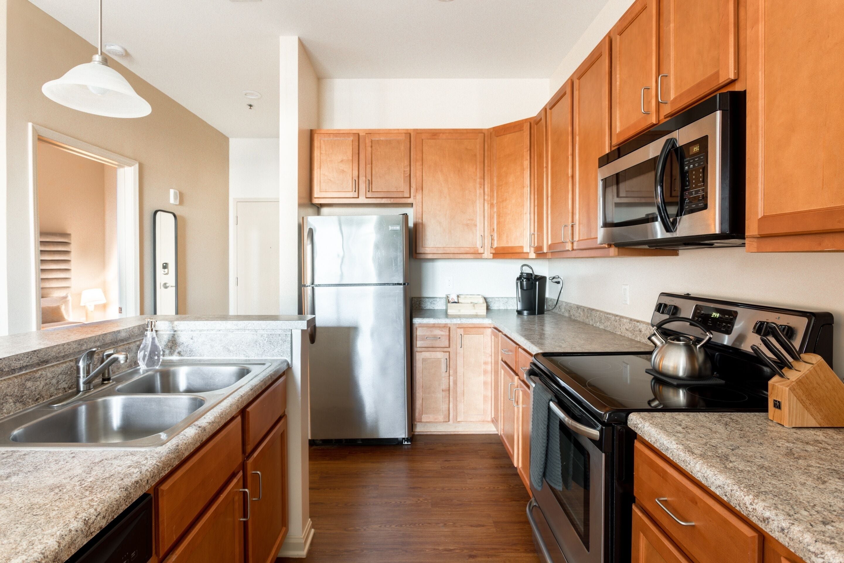 A modern kitchen with wooden cabinets, stainless steel appliances, granite countertops, and a built-in oven.