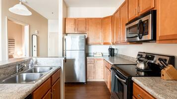 Una cocina moderna con gabinetes de madera, electrodomésticos de acero inoxidable, encimeras de granito y un horno empotrado.
