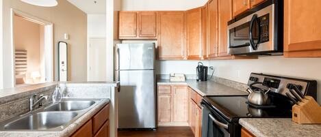 A modern kitchen with wooden cabinets, stainless steel appliances, granite countertops, and a built-in oven.