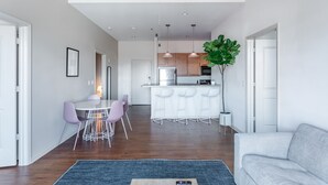 A modern kitchen with white cabinets, a stainless steel refrigerator, and a bar area with white stools. - Mint House Greenville Downtown by Kasa (Greenville)