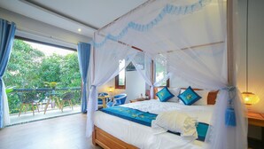A bedroom with a four-poster bed, a balcony with a table and chairs, and a view of greenery. - Sea Village Homestay (Da Nang)
