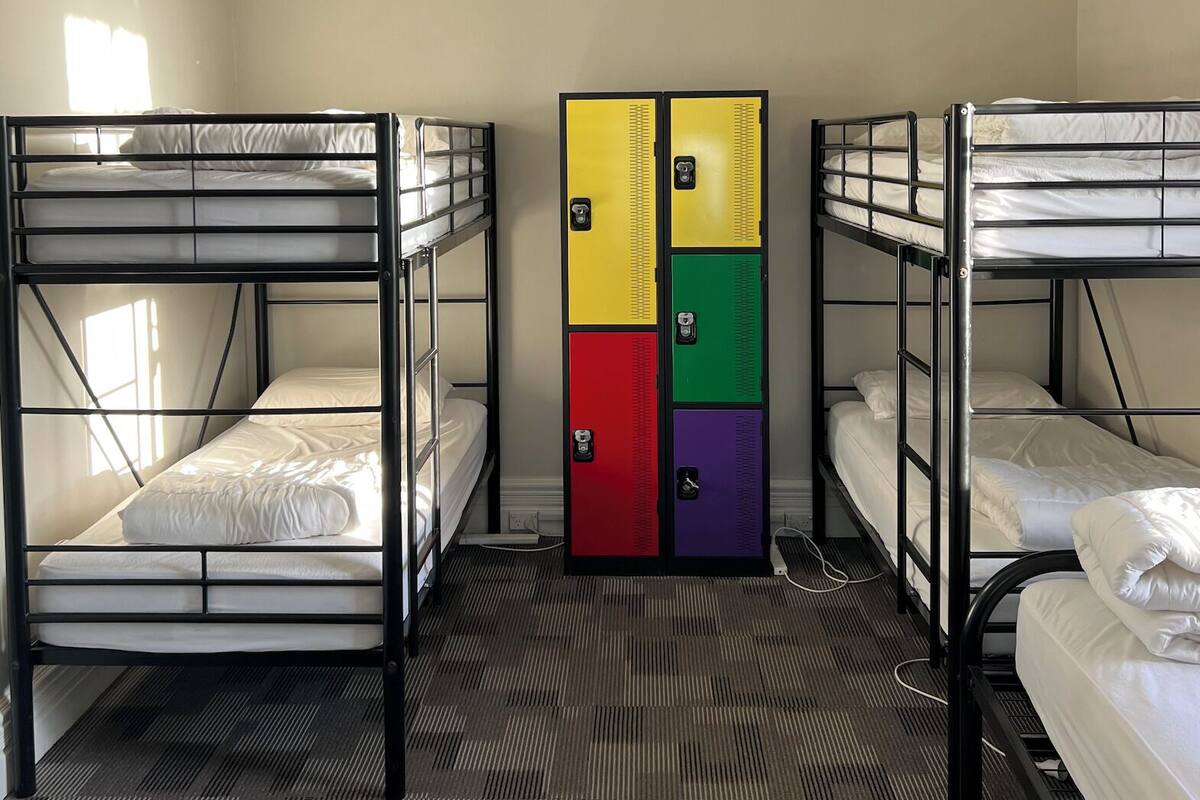 Un dormitorio con literas, una lámpara en el techo y varios taquillones.