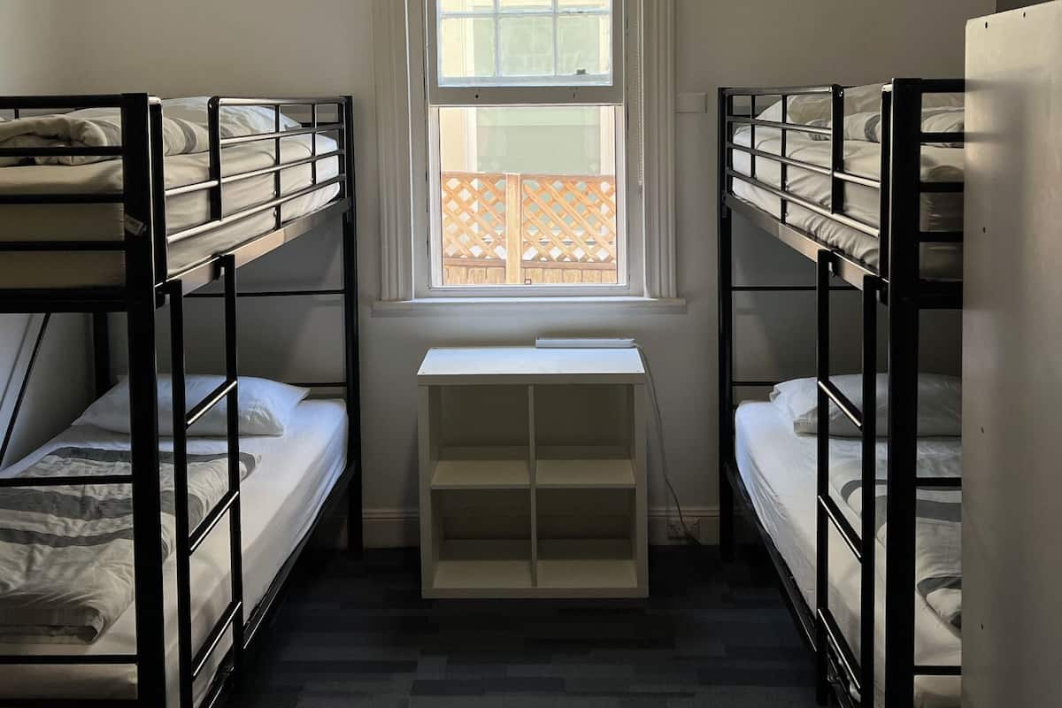 Una habitación pequeña y estrecha con literas a ambos lados de una ventana.