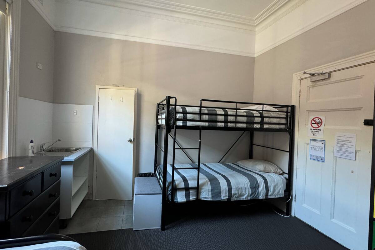 Habitación con literas, un escritorio y un lavabo.