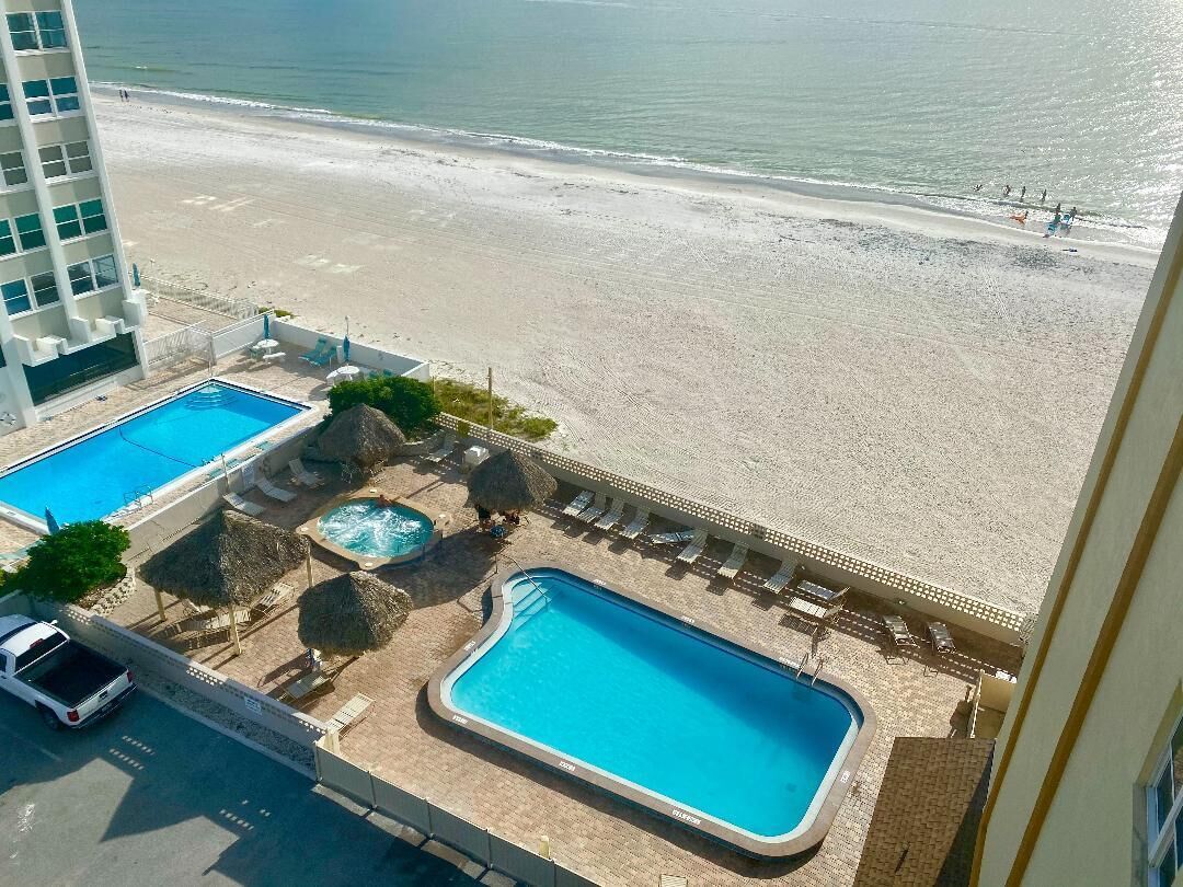 Hotel met een zwembad, inclusief een groot rechthoekig zwembad en een kleinere ronde hottub, omringd door ligbedden en parasols.