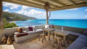A covered outdoor seating area with a view of the ocean and a mountainous landscape. - 5 bedroom villa with pool in stunning clifftop location next to gorgeous beach (Rogues Bay)