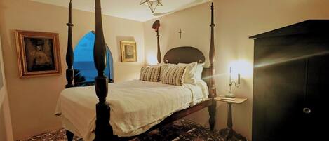 A four-poster bed with a star-shaped ceiling light, a bedside table with a lamp, and a patterned floor.
