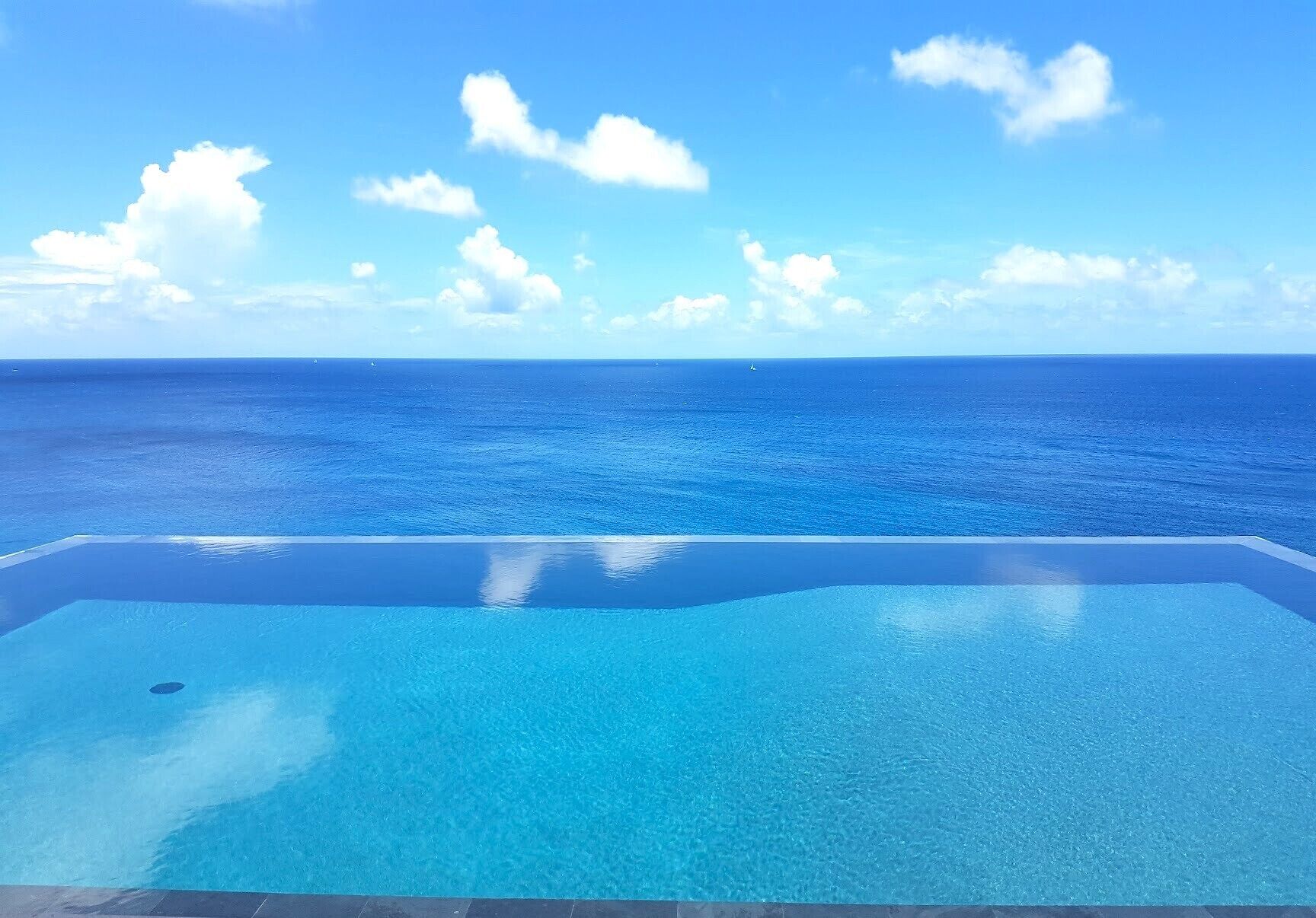 Una piscina infinita con vistas despejadas al océano y al cielo.