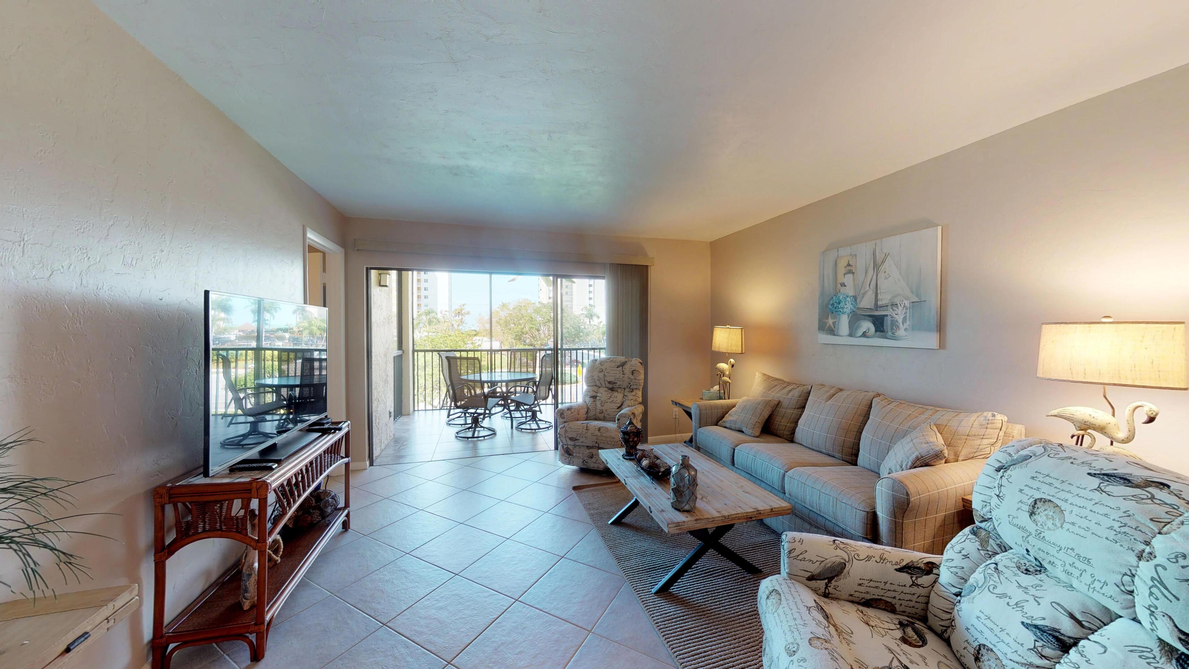 A living room with a television, sofa, armchair, and a dining area with a table and chairs.
