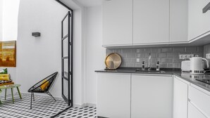 Een moderne keuken met witte kasten, een zwart aanrecht en een vloer met een patroon.