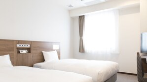 Quarto de hotel com duas camas, televisão e janela com cortinas.