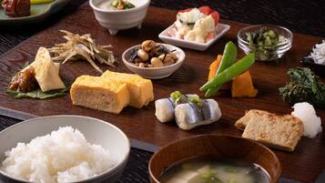 A variety of Japanese dishes including rice, tofu, fish, and vegetables on a wooden table.