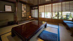A traditional Japanese room with tatami flooring, a shoji screen, a tatami mat bench, and a low table.