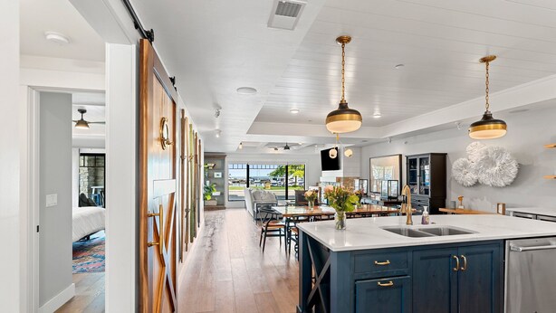 Een moderne keuken met een centraal eiland, donkerblauwe kastjes en hanglampen.