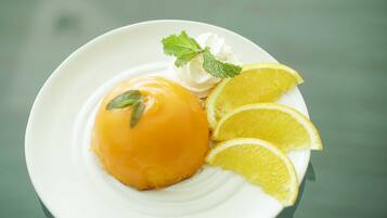 A dessert with a creamy topping, lemon slices, and mint leaves on a white plate.