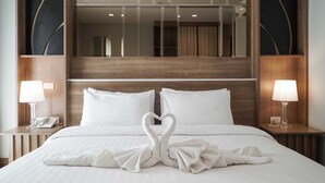 A hotel room with a large bed, two bedside lamps, a mirror above the bed, and a wooden headboard. - Nantra Chiangmai Riverfront Hotel (Chiang Mai)