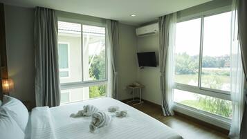 A hotel room with a large bed, a TV mounted on the wall, and a window with curtains.