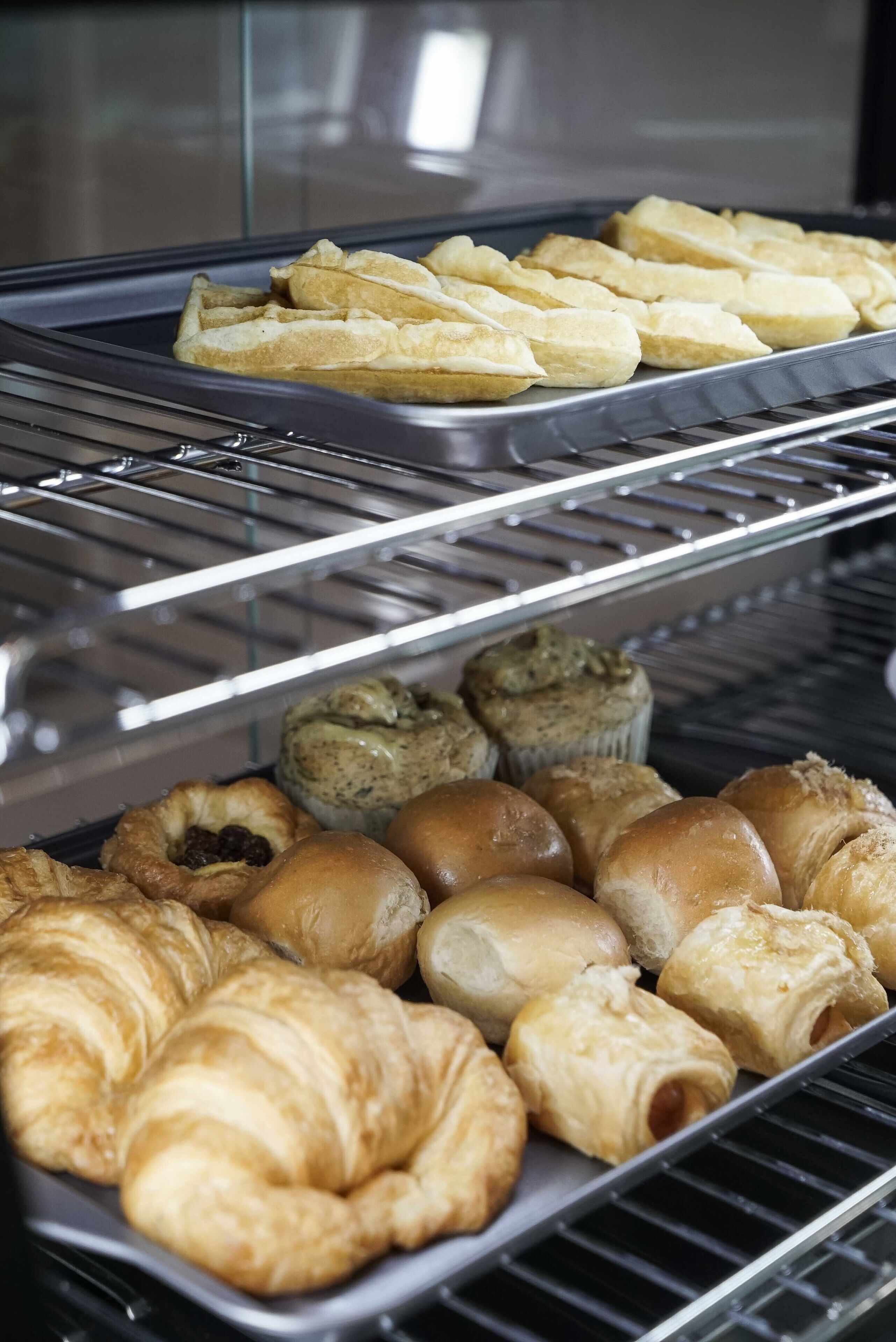Een bakkerijdisplay met diverse gebakjes zoals croissants en muffins.