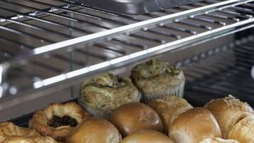Een bakkerijdisplay met diverse gebakjes zoals croissants en muffins.