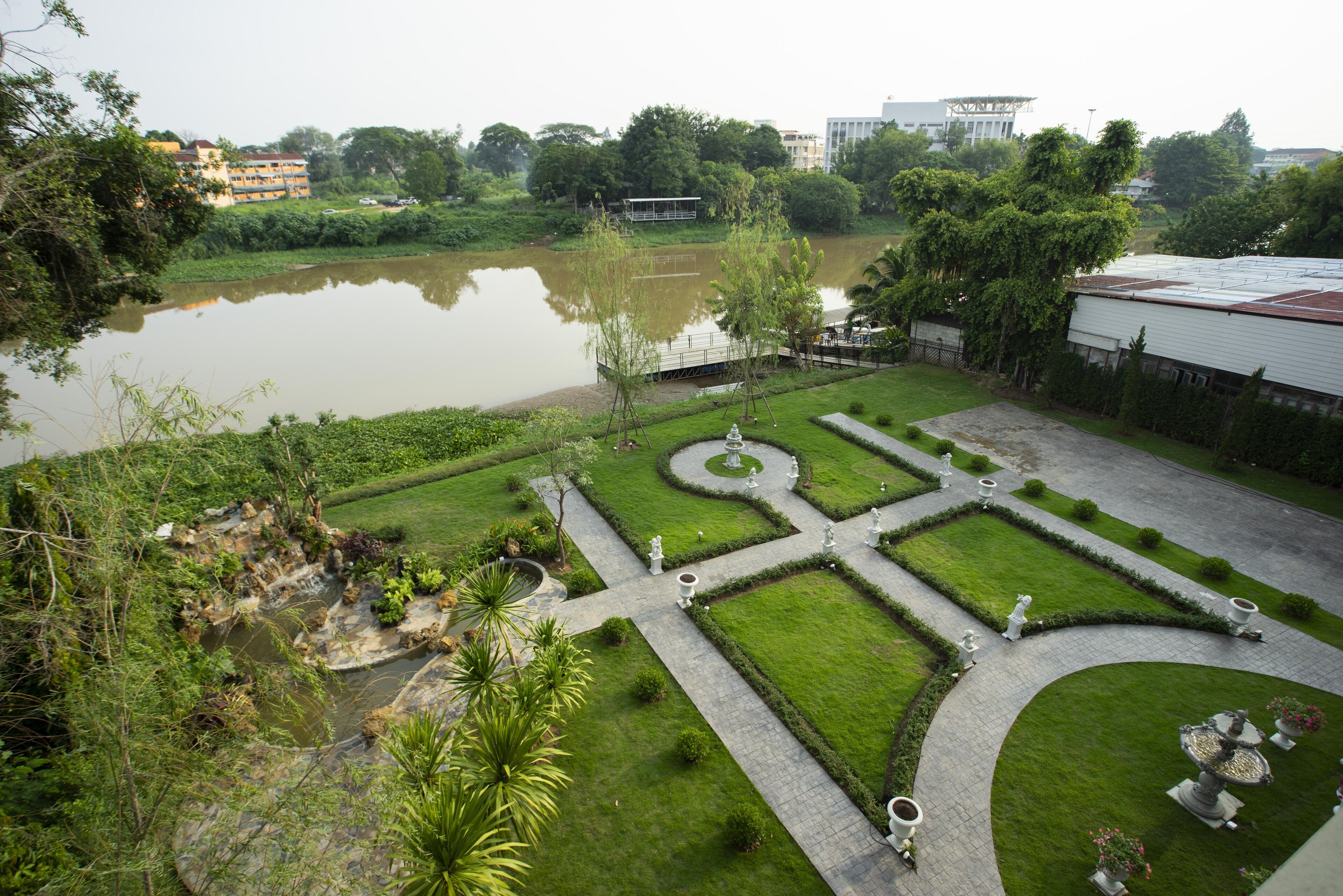 A landscaped garden with a pond, pathways, and statues.