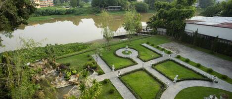 A landscaped garden with a pond, pathways, and statues.
