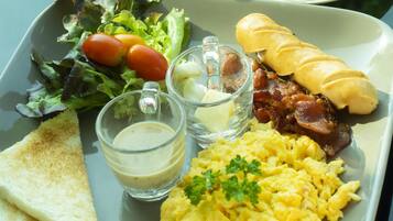 Un vassoio per la colazione con uova strapazzate, pancetta, pane tostato, un'insalata e una tazza di caffè su un tavolo, con un prato verde sullo sfondo.