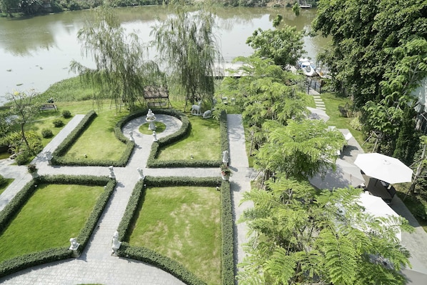 Un jardín ajardinado con un estanque, senderos y estatuas.