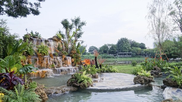 A serene garden with a waterfall, lush greenery, and a small pond. - Nantra Chiangmai Riverfront Hotel (Chiang Mai)