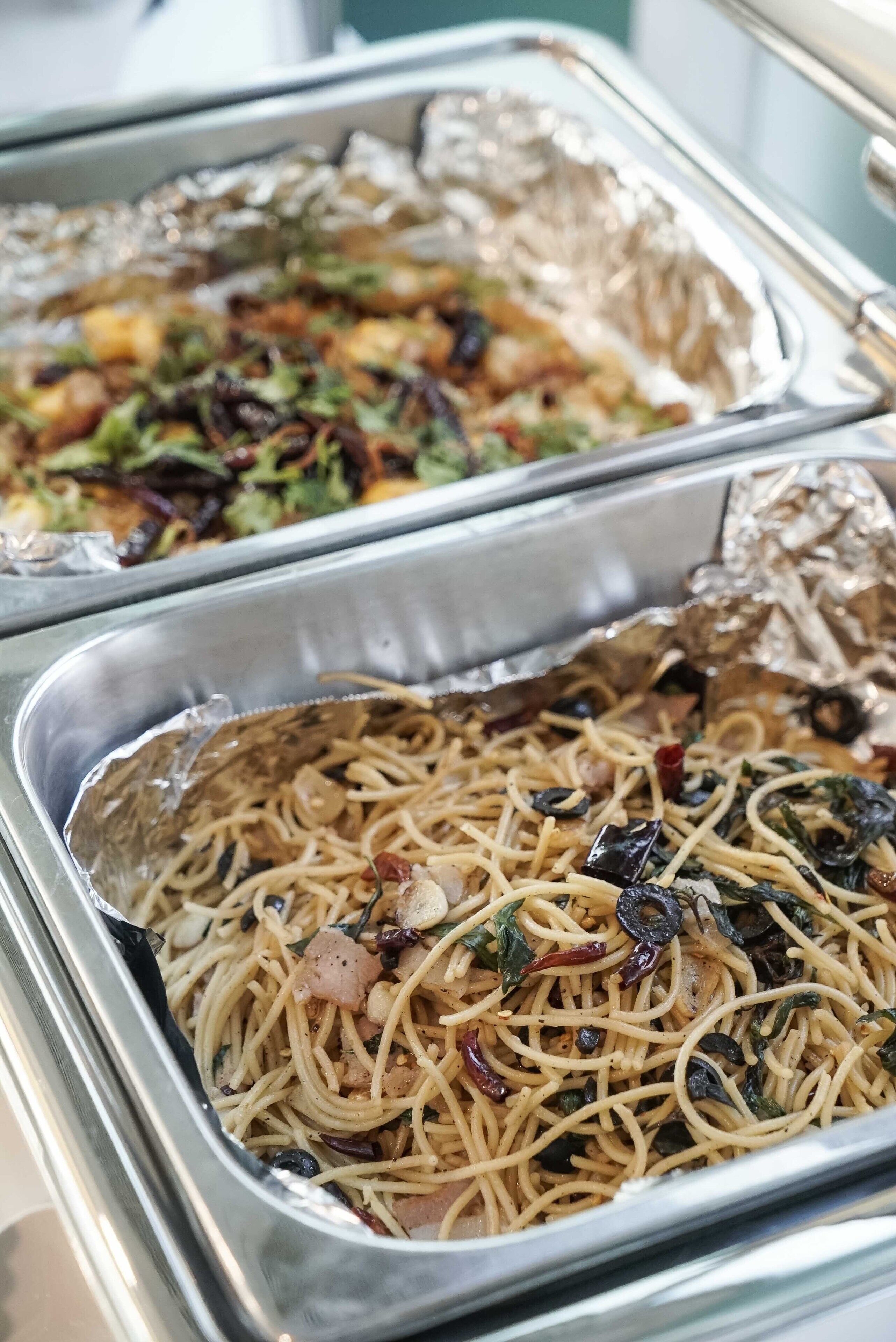 Ein Buffet mit verschiedenen Speisen, darunter Nudeln und Salate.