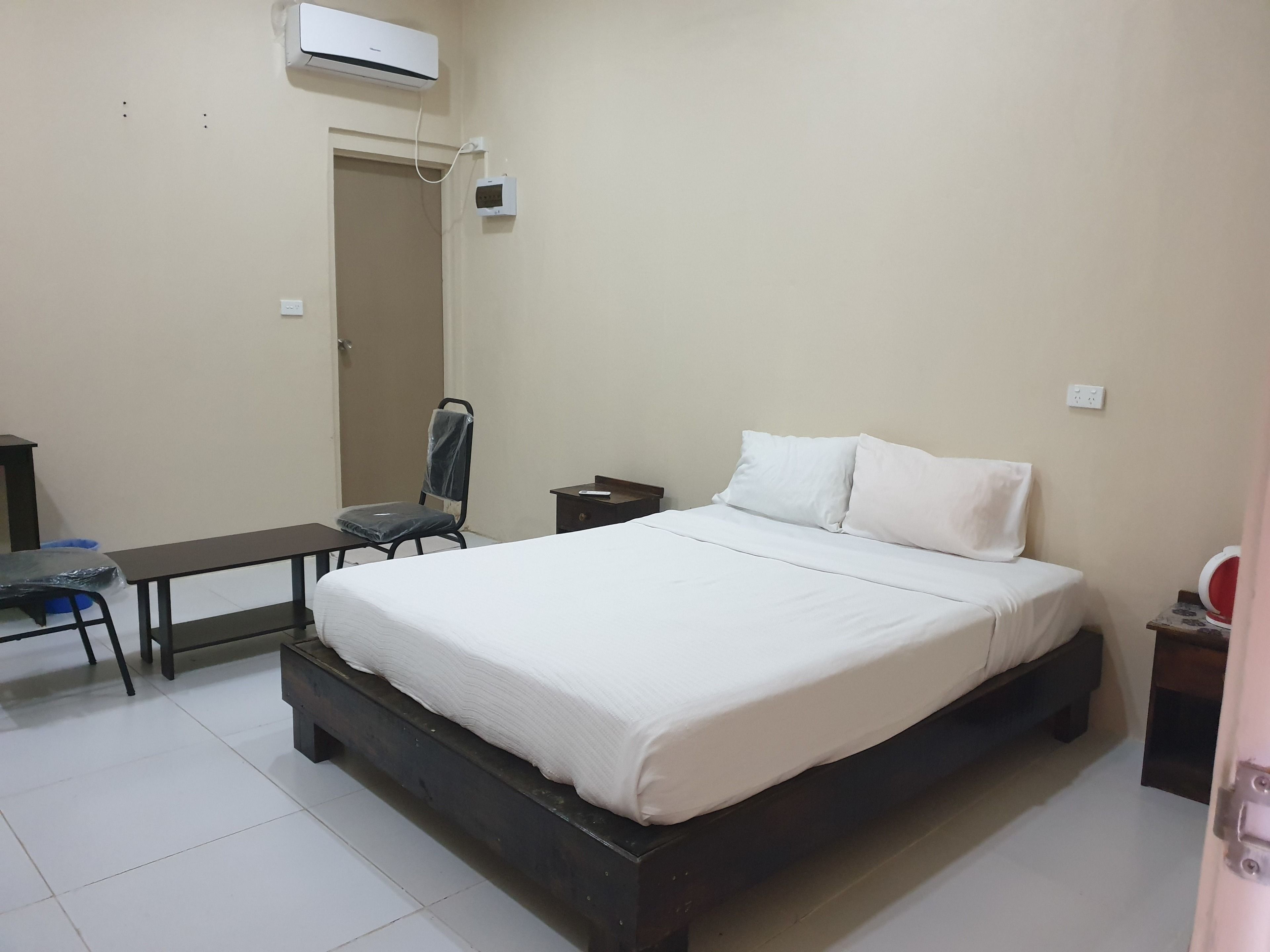 A bedroom with a bed, a chair, a desk, and a small table.