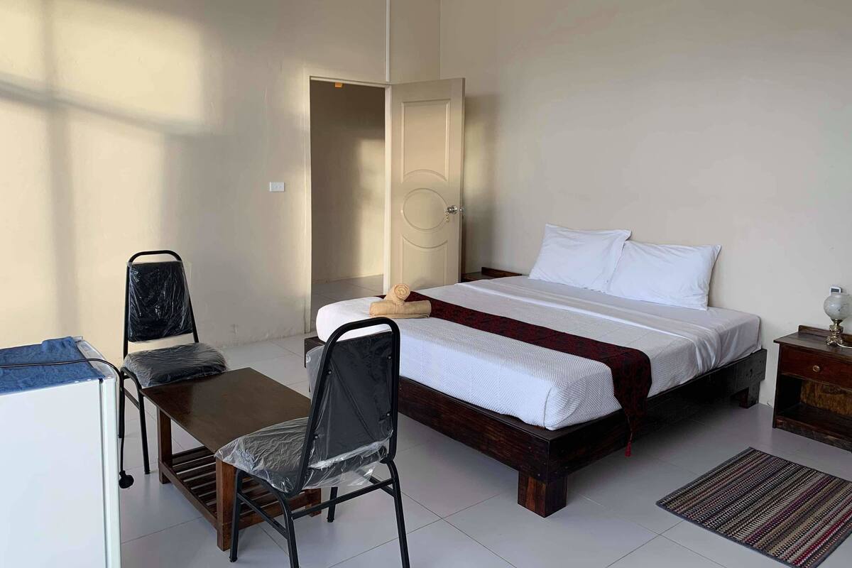 A bedroom with a bed, a desk, a chair, and a nightstand.