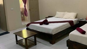 A hotel room with two beds, a small table, and a door leading to an outdoor area. - Bay View Barbers Lodge (Savusavu)